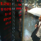 A man looking at stock prices during rain in Tokyo, 2002.